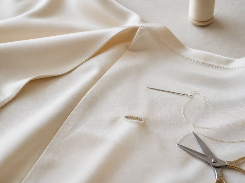 Kleiner Riss in einem Seidenkleid vor der Reparatur